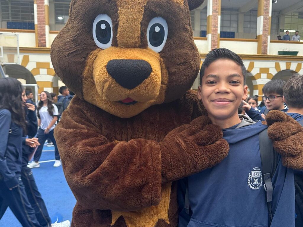 Estudiante del Colegio Champagnat posando con Monty, la mascota institucional